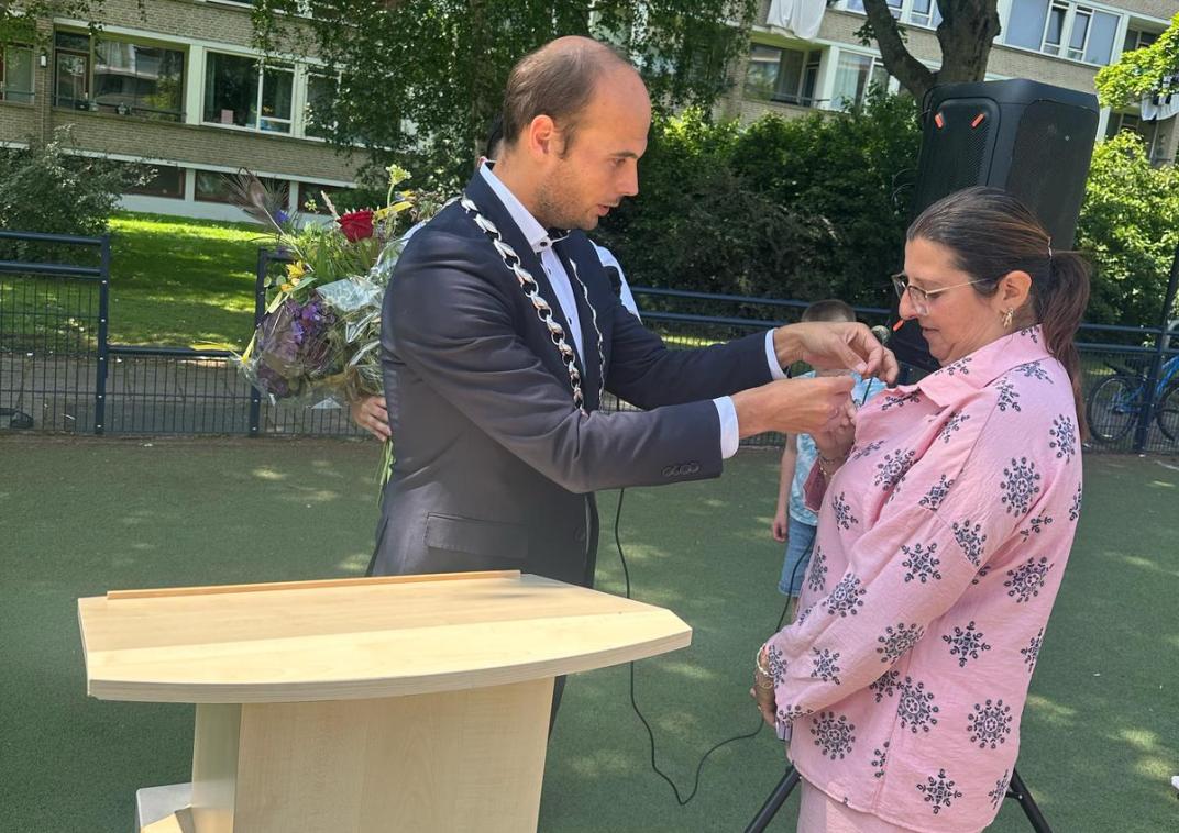 Gijs van Malsen plaatst een speld op de blouse van Zora als Rijswijks Compliment