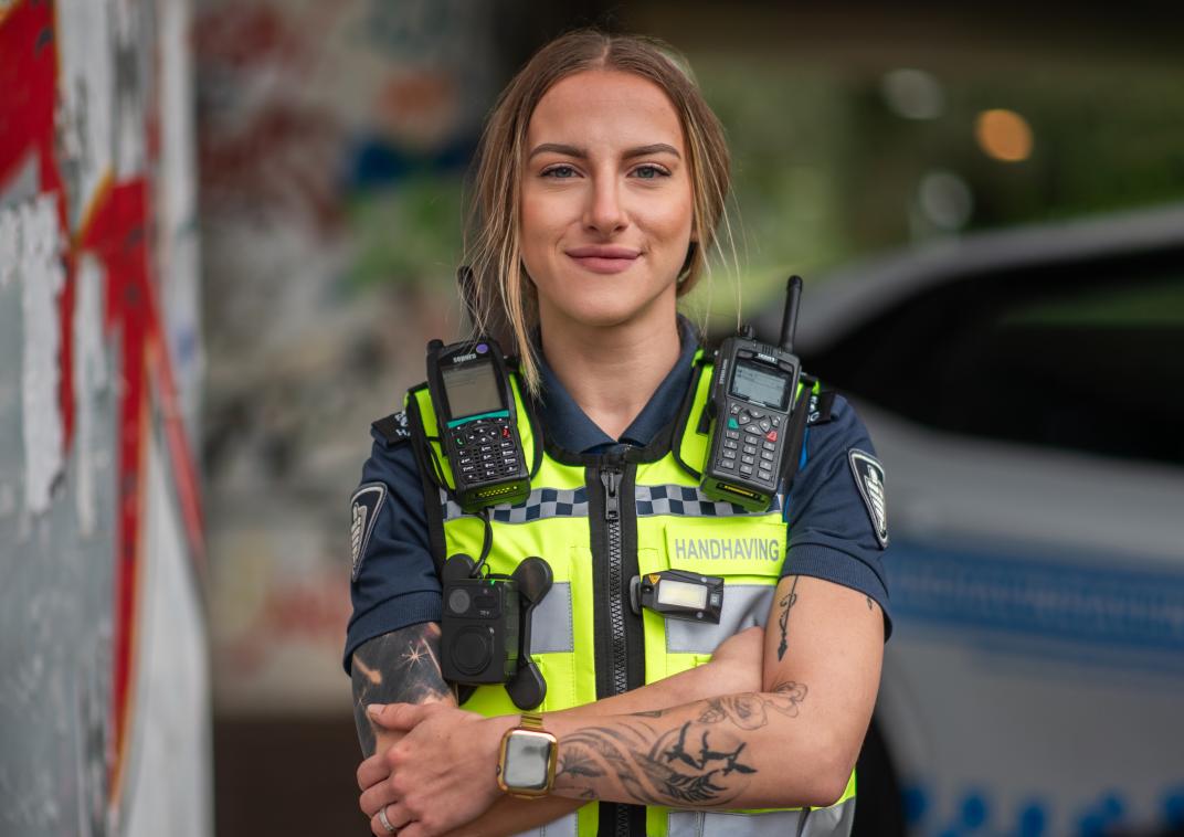 Vrouwelijke jeugd boa in uniform. Ze kijkt recht in de camera en heeft tatoeages op haar armen.