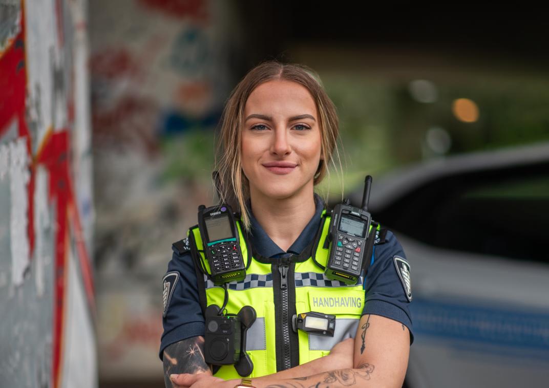 Vrouwelijke jeugd boa in uniform. Ze kijkt recht in de camera en heeft tatoeages op haar armen.