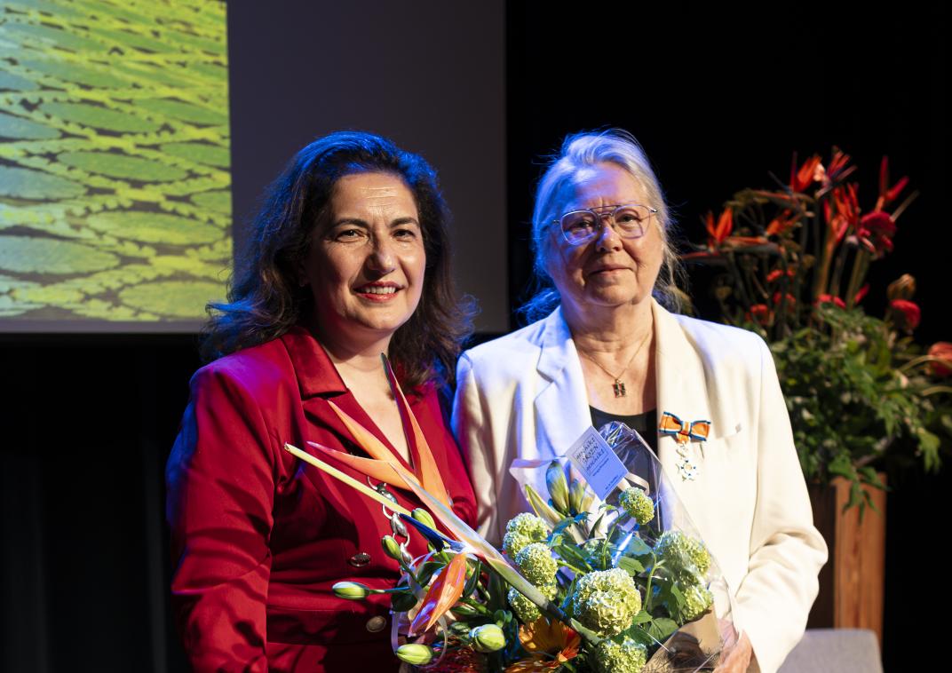 mevrouw met bos bloemen in haar handen en een lintje op haar jasje gespeld
