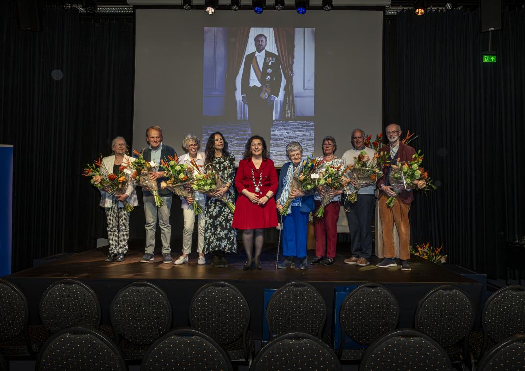 mensen op het podium met een lintje en bos bloemen