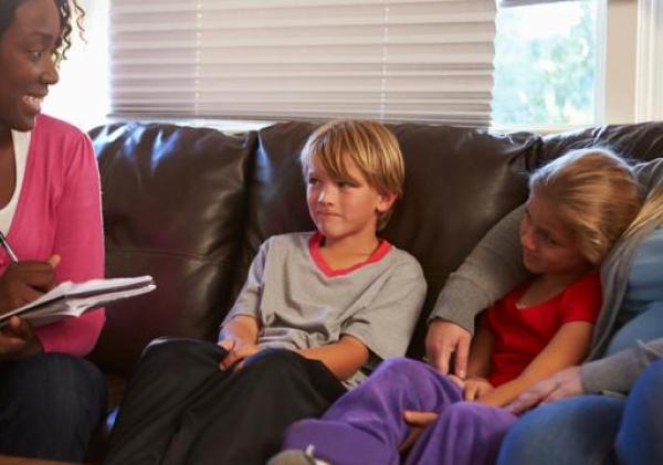 Vrouw maakt notities terwijl ze op de bank zit bij twee kinderen en hun moeder
