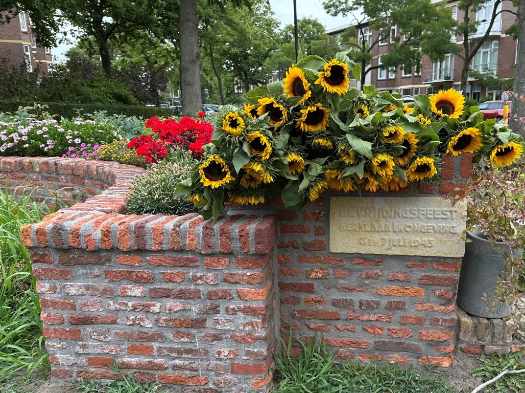 Bloemen liggend op een stenen bloembak bij de gedenkplaats 