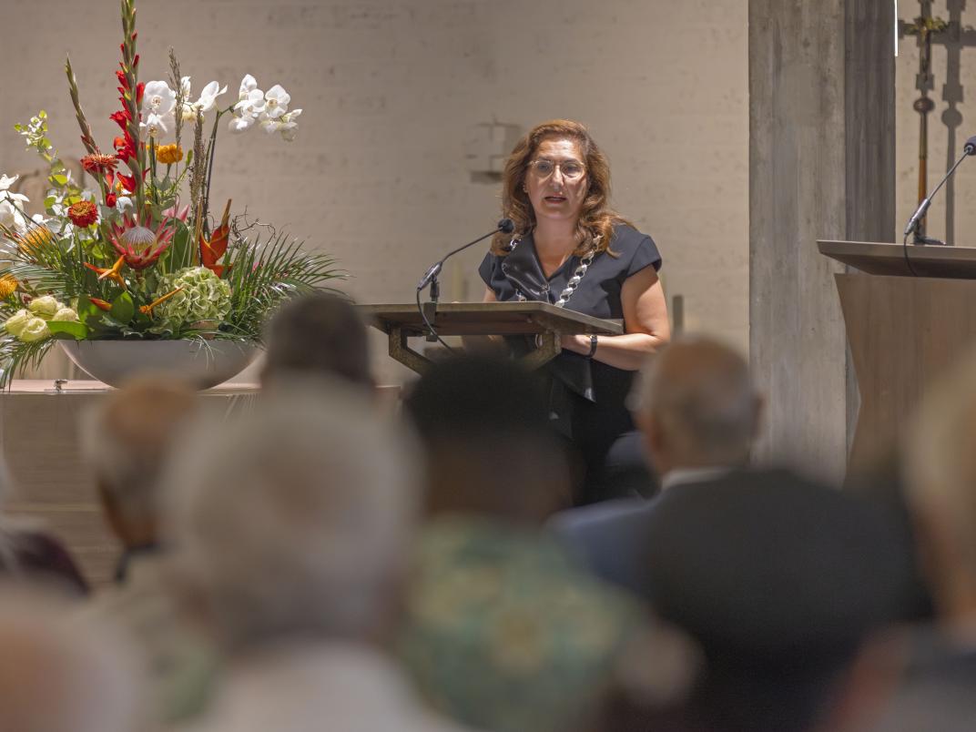 Burgemeester Huri Sahin staat achter een microfoon en spreekt het publiek toe