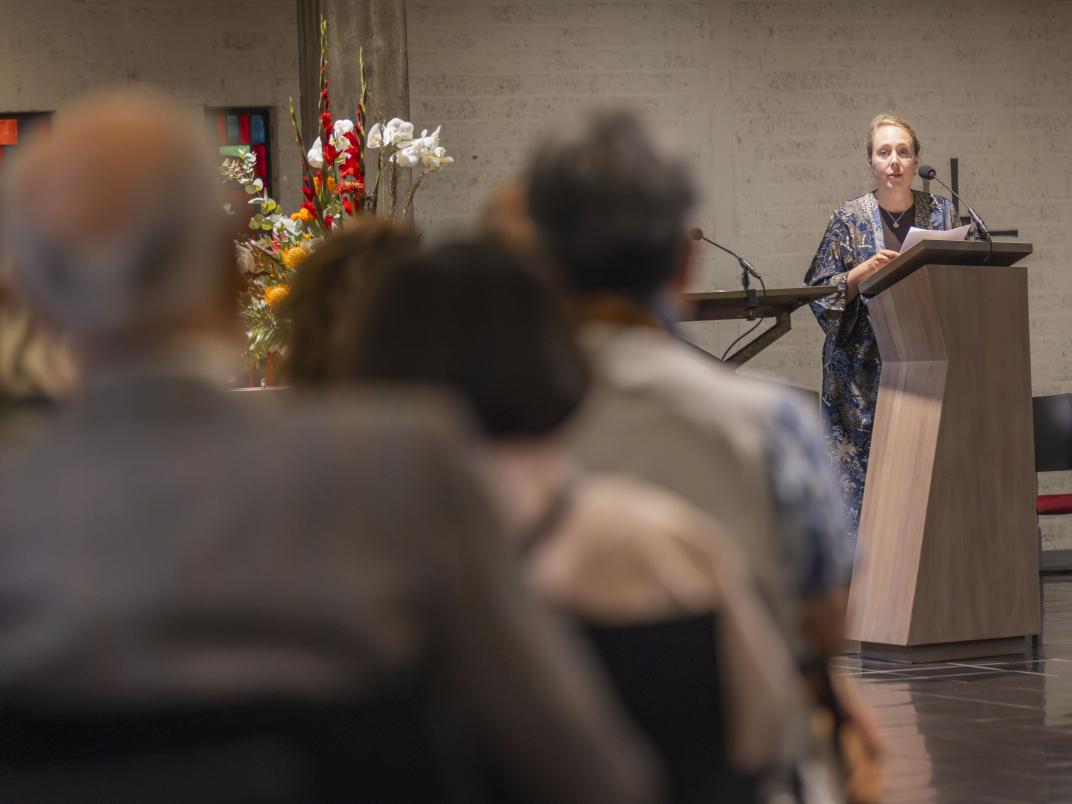 Een vrouw staat met een microfoon in haar hand en spreekt het publiek toe