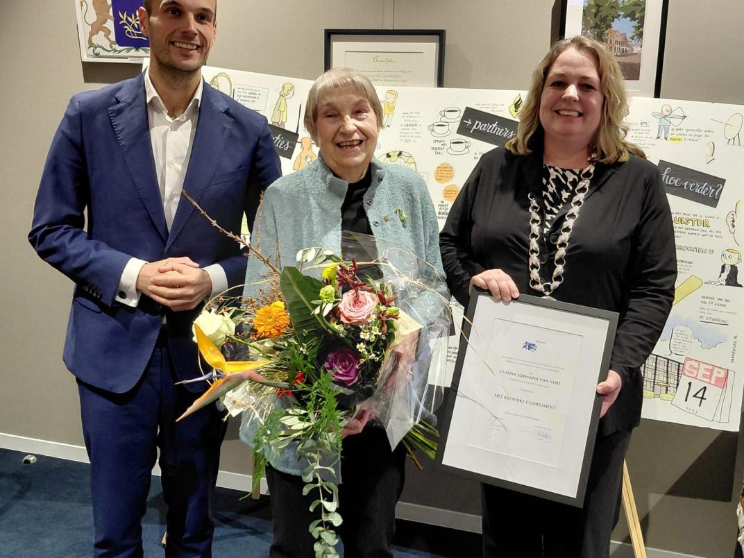 Wethouder Gijs van Malsen en Sandra van de Waart samen met Ineke van Vliet en een bos bloemen
