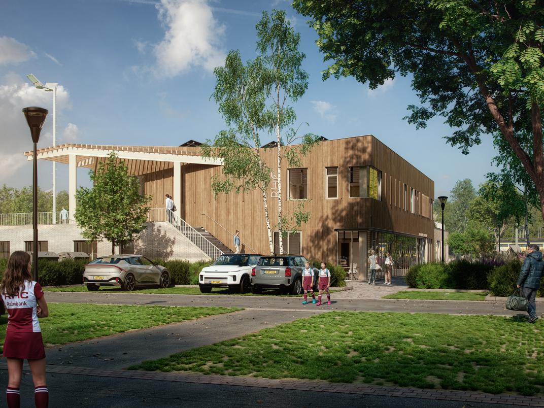 Parkeerterrein van MFA sportpark Rijswijk. Op de voorgrond staan twee tienermeiden in een hockey outfit. Op de parkeerplaats staan wat auto's geparkeerd. Daarachter is het clubhuis te zien. 