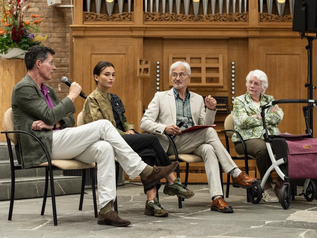 Vier personen voeren met elkaar een gesprek voor het publiek. 