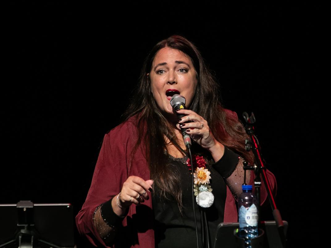Een vrouw zingt uit volle borst met een microfoon voor haar mond.