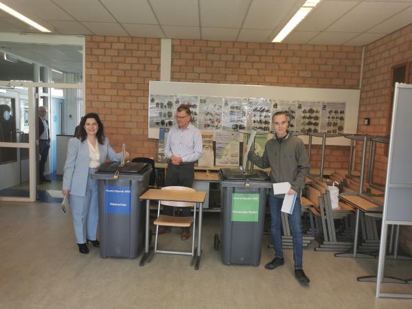 Foto waarop Burgemeester Huri Sahin een stem uit brengt samen met een 18-jarige Rijswijker die voor het eerst mag stemmen. Voorzitter van het stembureau Hans Lunter kijkt toe.