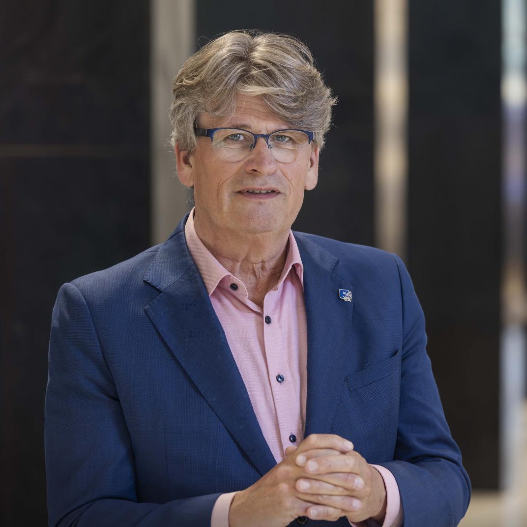 Portret van een meneer met zijn handen over elkaar in een statige hal